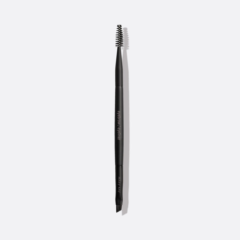 Pinceau double pour les sourcils et les yeux Mary Kay sur un fond uni.