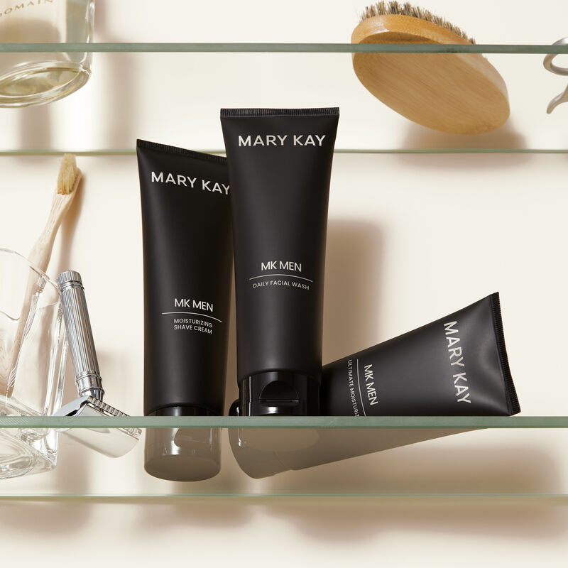Cr&egrave;me &agrave; raser hydratante MKMen, Nettoyant facial quotidien MKMen et Hydratant ultime MKMen sur une &eacute;tag&egrave;re &agrave; c&ocirc;t&eacute; d&rsquo;un rasoir, d&rsquo;une brosse pour homme et d&rsquo;autres articles de toilette