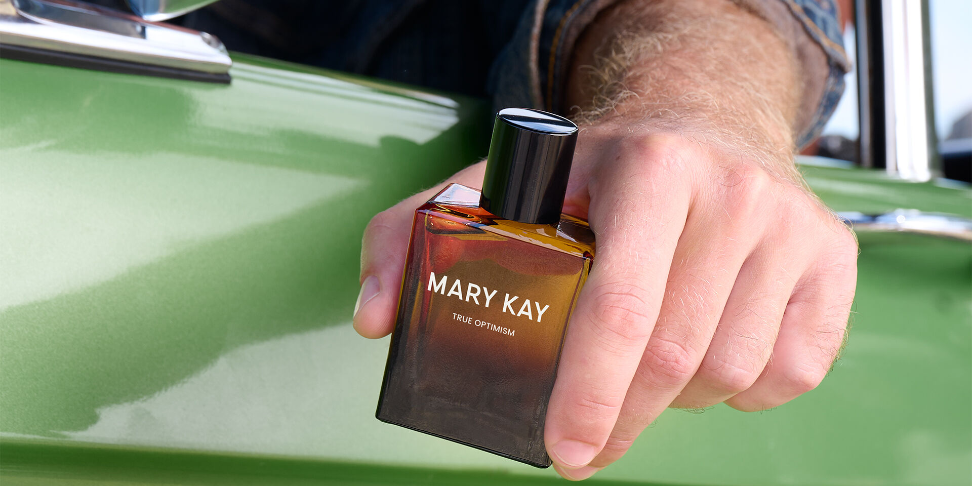 light skin tone model&rsquo;s hand holds Mary Kay&reg; True Optimism&trade; Eau de Parfum out of the window of a green car