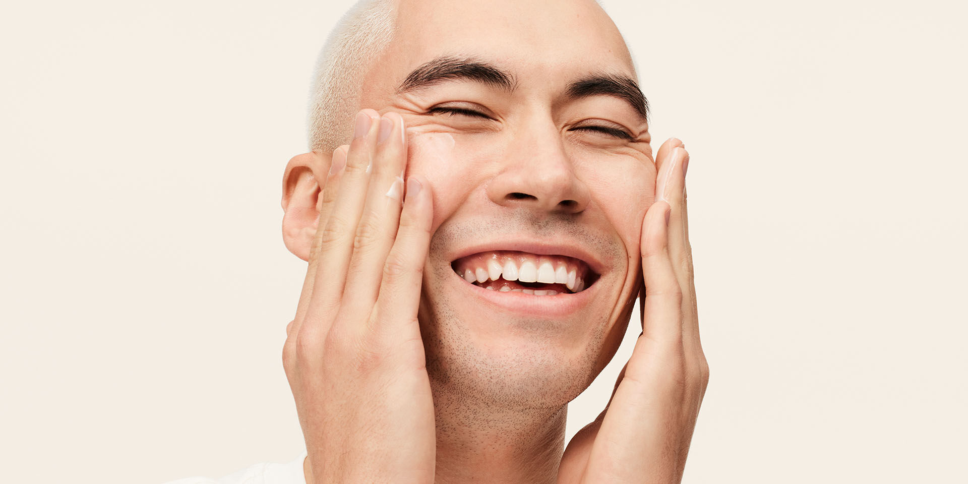 Mannequin homme souriant et appliquant l'Hydratant MKMen sur son visage